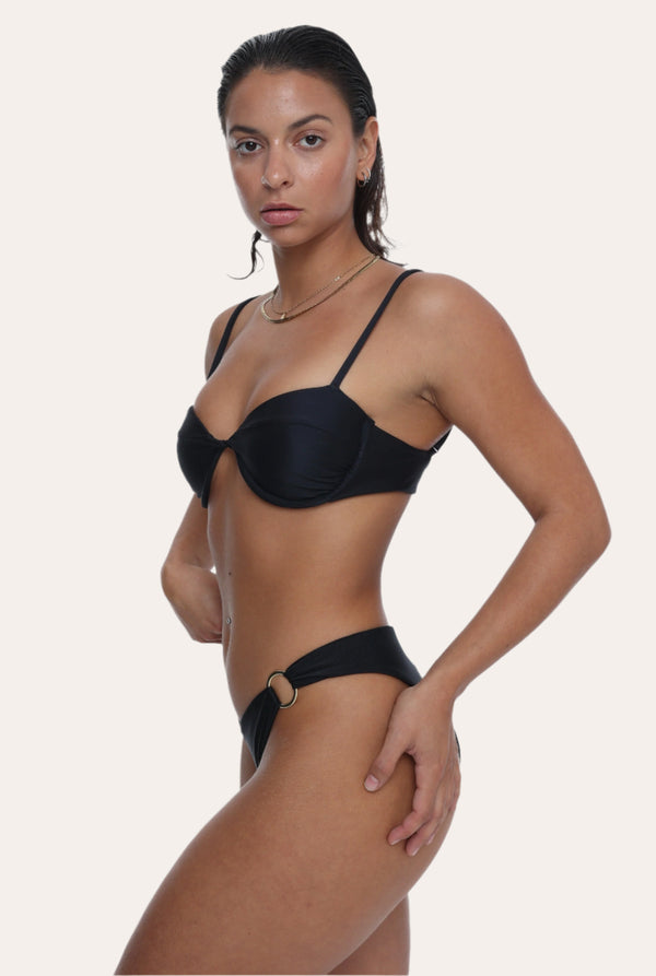 Amour black bikini Bottoms in Onyx with a gold ring, Sustainable recycled swimwear luxury bikini, seen on a model from the side