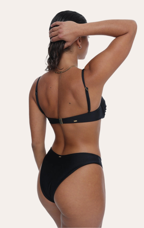  Amour black bikini Bottoms in Onyx with a gold ring, Sustainable recycled swimwear luxury bikini, seen on a model from the back raising one arm holding her hair